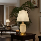 Đèn để bàn trang trí DB70T thân sứ màu kem, chụp vải trắng, đế xi vàng, mang ánh sáng ấm áp cho không gian phòng khách và phòng ngủ.